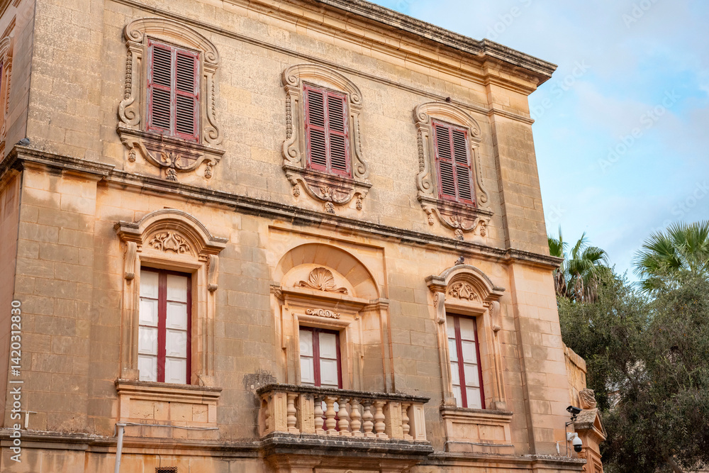Fototapeta premium Narrow streets of the old of Valletta on Malta with colourful balconies and red telephone boxes.Red traditional maltese balconies. Facade of old traditional building with red windows and balconies 
