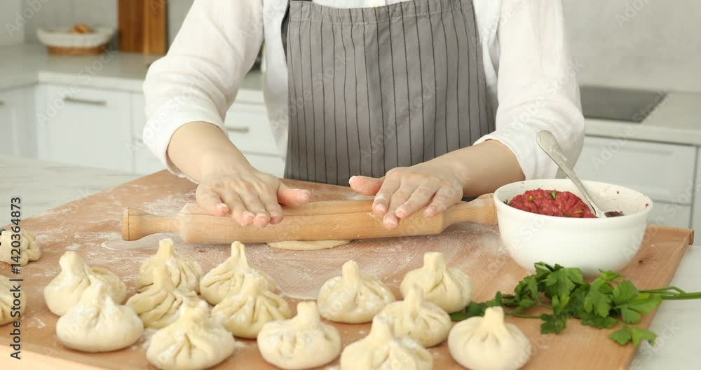 Making khinkali. Woman with rolling pin shaping piece of dough at table in kitchen, closeup Making khinkali. Woman with rolling pin shaping piece of dough at table in kitchen, closeup