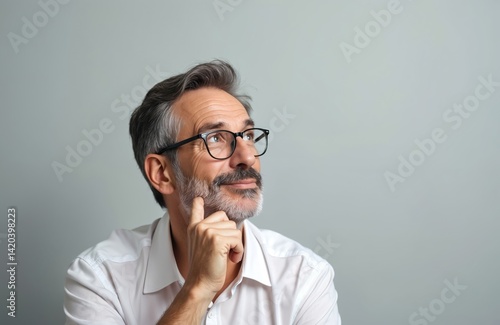 Obraz na płótnie Mature man with glasses looks upwards thinking about project plan, strategy. Grey hair beard on pastel background. Smart, clever man with thoughtful face at work. w salonie