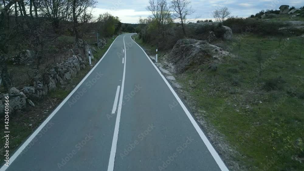 (DRON) vista aérea de una carretera solitaria de dos sentidos en una zona rural de montaña. Madrid, España, abril 2025.