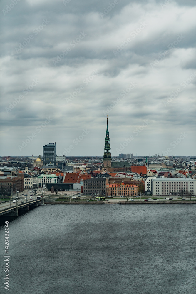 Fototapeta premium Cold cloudy city scape of Riga, vertical photo of old town Riga next to river Daugava