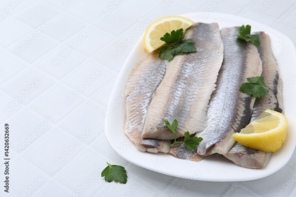 Marinated herring fillets with lemon and parsley on white tiled table, closeup. Space for text Marinated herring fillets with lemon and parsley on white tiled table, closeup. Space for text