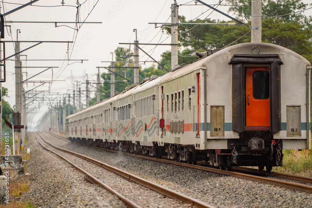 Passenger train of PT KAI moves through West Java's railway network, framed by overhead wires and greenery on both sides. Passenger train of PT KAI moves through West Java's railway network, framed by overhead wires and greenery on both sides.