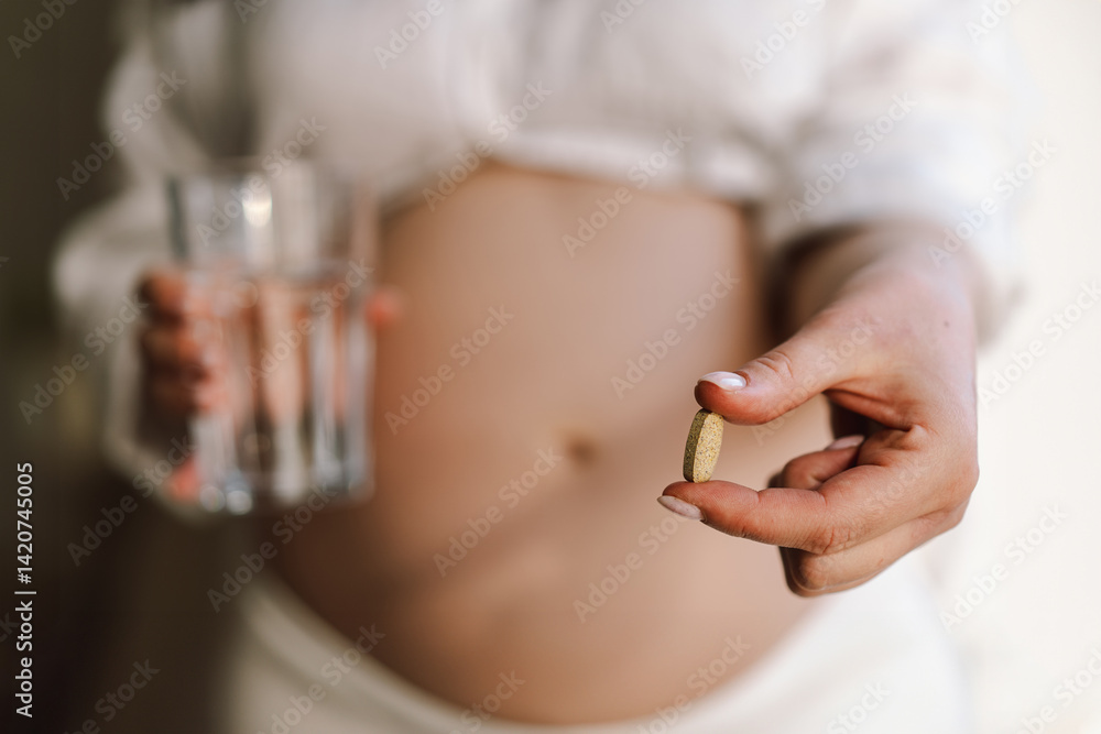 Fototapeta premium Pregnant young woman holding vitamins to maintain health of herself and her baby. Pregnancy and Health Concept