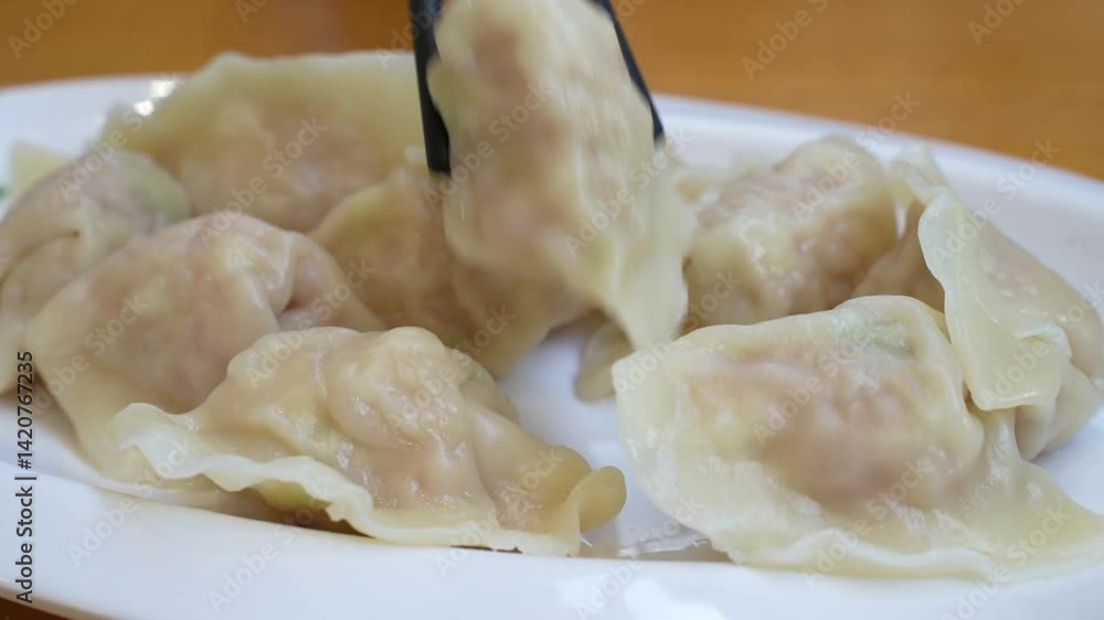 picking up boiled dumplings from white plate by chopsticks picking up boiled dumplings from white plate by chopsticks