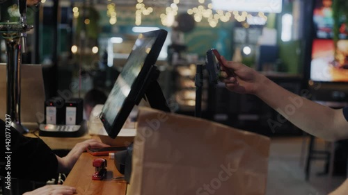 A cashier enters an order on a touchscreen register, the customer pays by card, the receipt prints, and the food is handed over in a cardboard box.