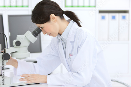 顕微鏡を見る白衣の女性