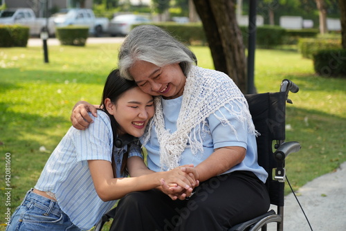 Two women, the daughter pushing a stroller with her elderly mother, walk in the garden and chat happily.