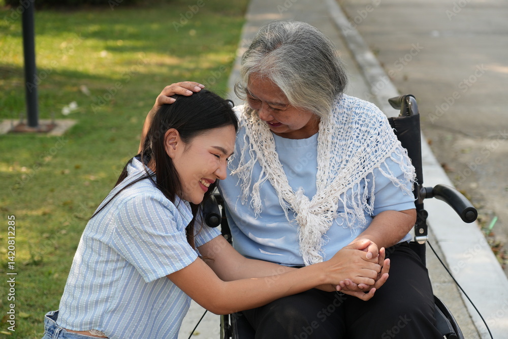 Two women, the daughter pushing a stroller with her elderly mother, walk in the garden and chat happily.