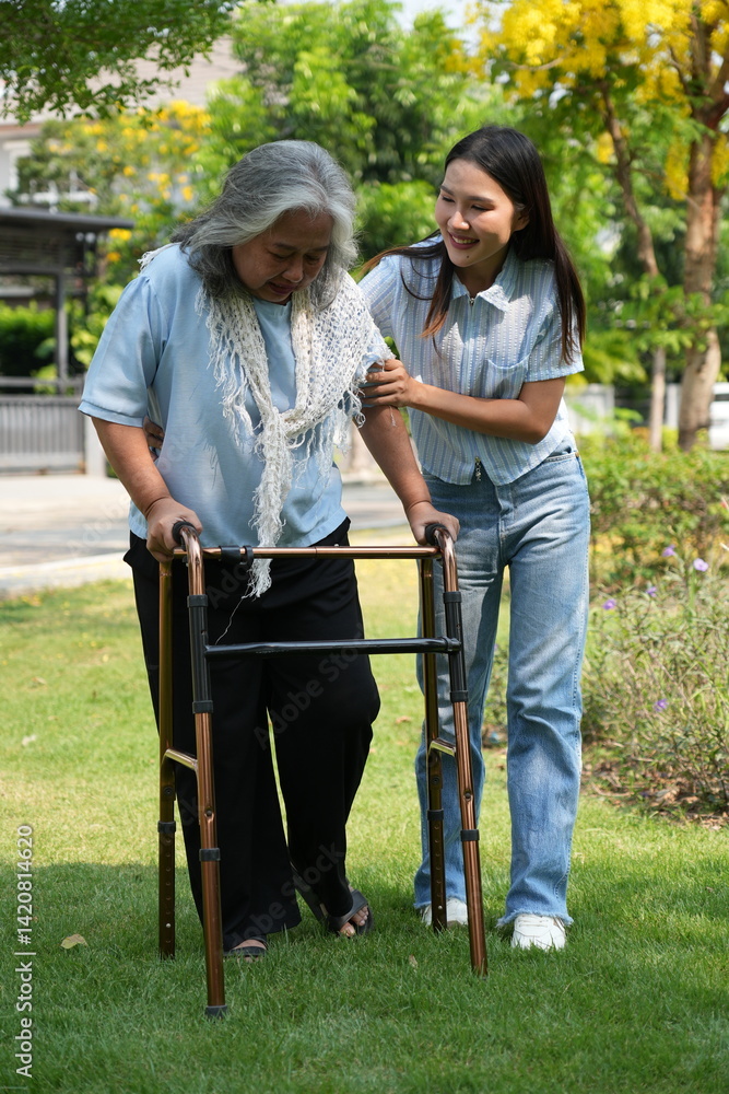 Two women, the daughter pushing a stroller with her elderly mother, walk in the garden and chat happily.