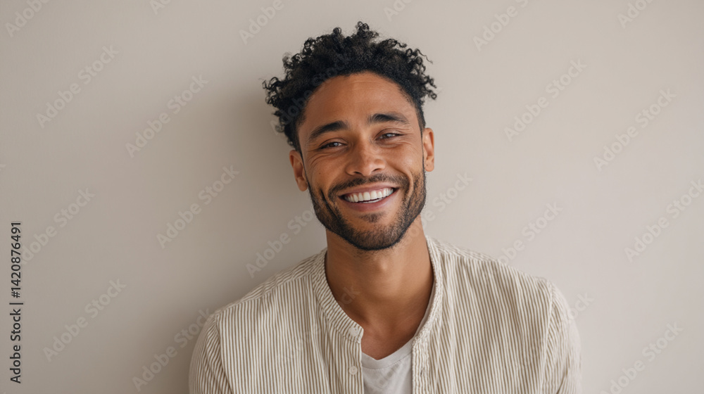 Portrait of handsome smiling man with curly hair and striped shirt against a neutral background Portrait of handsome smiling man with curly hair and striped shirt against a neutral background