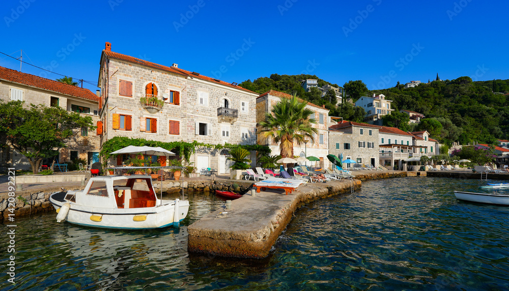 Fototapeta premium Waterfront promenade of Rose, a fishing village at the tip of the Luštica Peninsula on the eastern shore of the mouth of the bay of Kotor along the coast of the Adriatic Sea in Montenegro