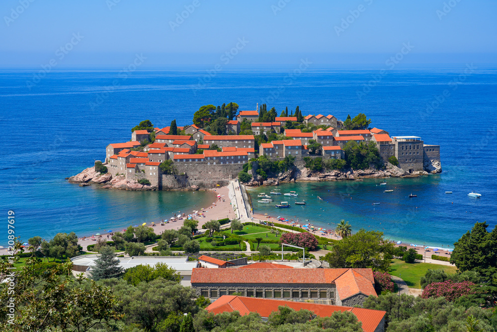 Aerial view of Sveti Stefan, a medieval village located on a small island connected to the mainland by a narrow tombolo (sandy isthmus) in the bay of Budva along the Adriatic Coast, Montenegro