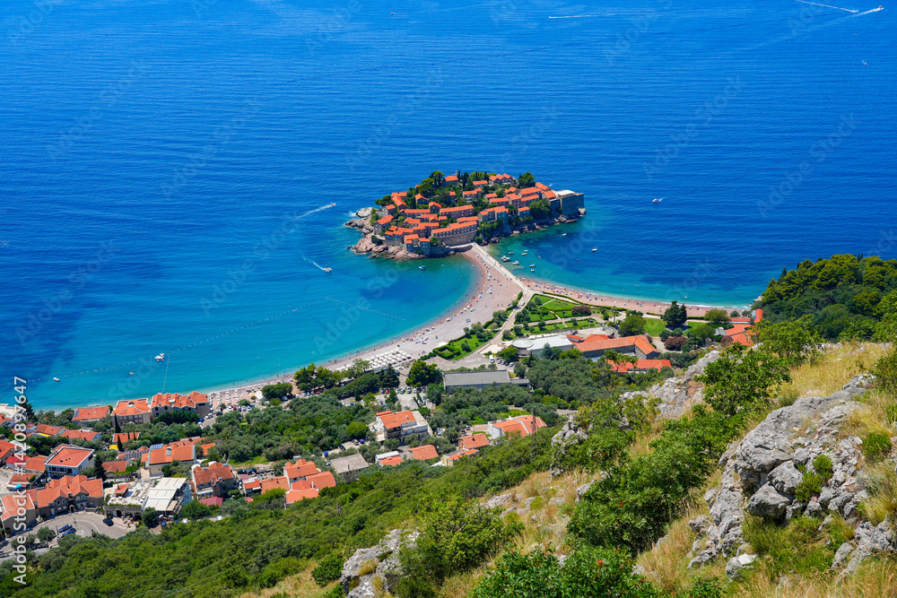 Aerial view of Sveti Stefan, a medieval village located on a small island connected to the mainland by a narrow tombolo (sandy isthmus) in the bay of Budva along the Adriatic Coast, Montenegro