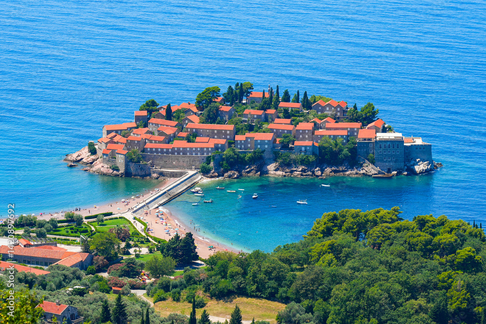 Aerial view of Sveti Stefan, a medieval village located on a small island connected to the mainland by a narrow tombolo (sandy isthmus) in the bay of Budva along the Adriatic Coast, Montenegro