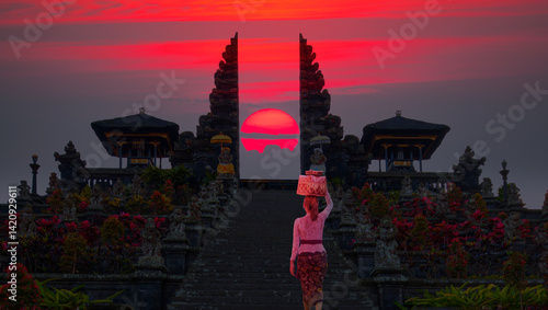 Obraz na płótnie Beautiful balinese girl walking in traditional costume - Pura Besakih temple on the slopes of Mount Agung largest and holiest temple at red sunset - Bali, Indonesia w salonie