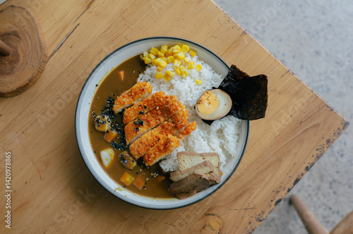 A plate of Japanese chicken katsu curry served with rice, egg, and seaweed