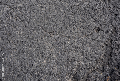 Nahaufnahme einer grau-schwarzen Lava-Textur auf dem Boden. Porös, rissig und steinern, ideal als Stock-Textur oder Foto-Hintergrund. Eindruck von geschmolzenem Gestein.
