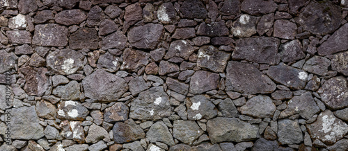 Textur Nahaufnahme einer Natursteinmauer aus Lavasteinen auf den Azoren, Portugal. Ohne Mörtel geschichtet, zeigt sie eine rustikale und natürliche Ästhetik. Eindruck von Stabilität und Tradition.