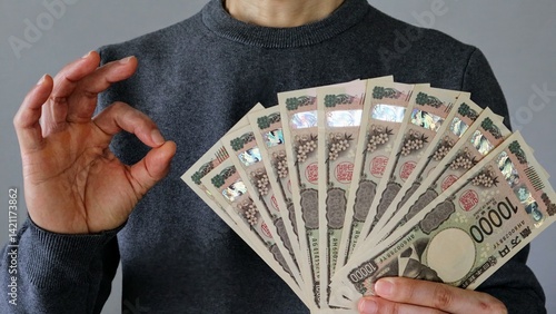 大量の一万円札を持ちポーズする人物