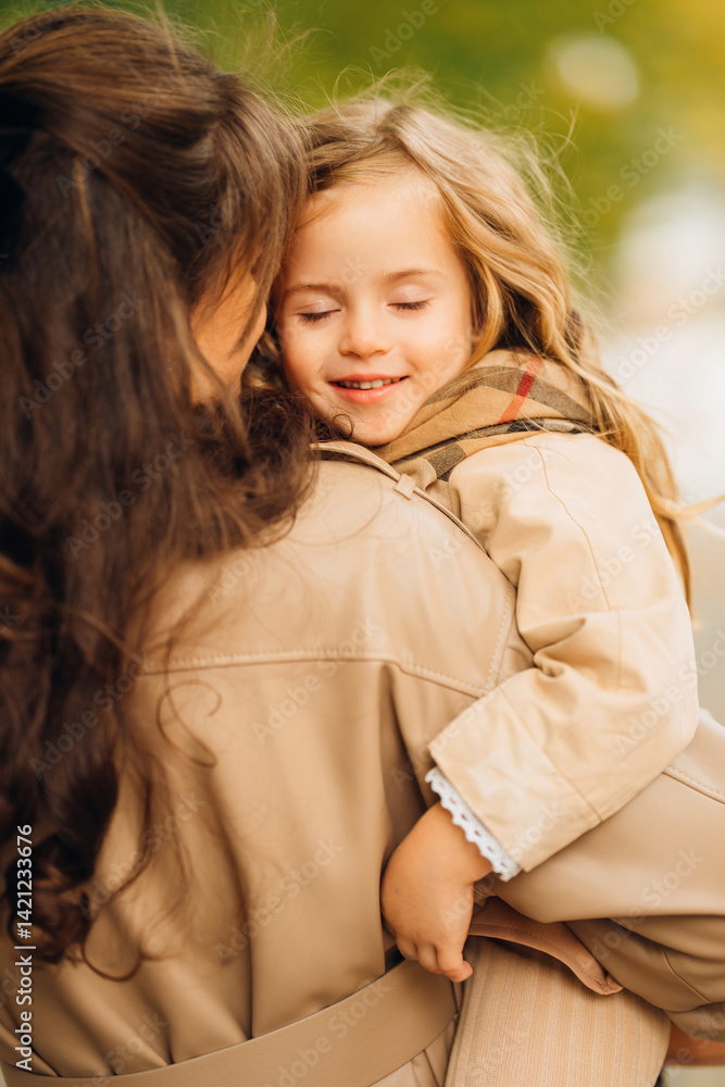 Child smiles while being held by parent in a sunny outdoor setting