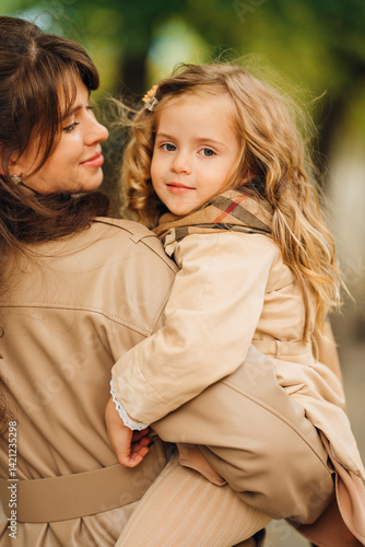 Mother carrying daughter in warm fall weather at a park