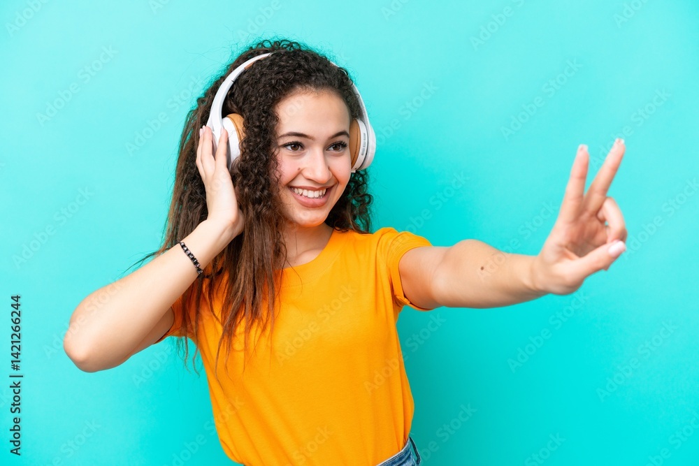 Fototapeta premium Young Arab woman isolated on blue background listening music and singing