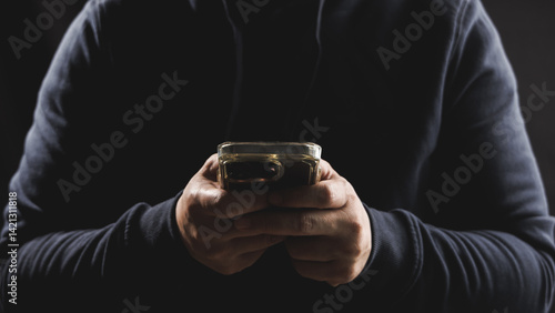 Man hand using smartphone in dark and moody tone. Concept of cybersecurity technology.