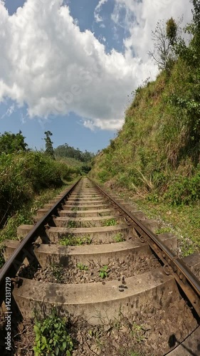 Walking along the historic railway tracks near Ella, Sri Lanka, surrounded by lush greenery and bathed in warm sunlight