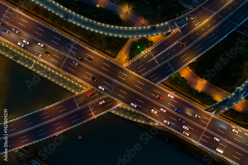 Aerial view of a busy road junction during nighttime with illuminated highways and moving vehicles.
