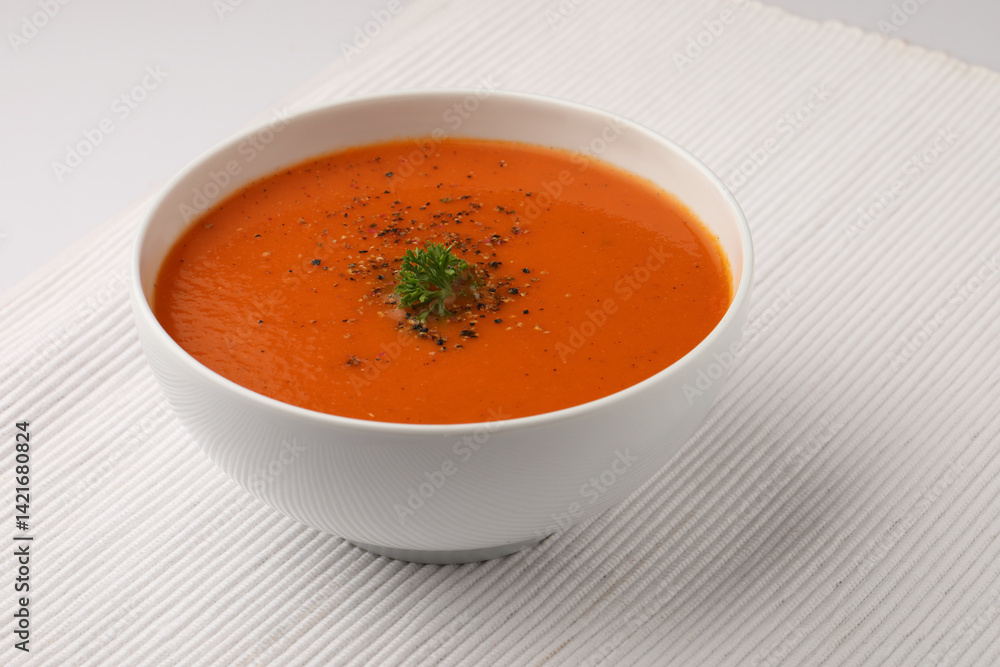 bowl of tomato soup with parsley on white background bowl of tomato soup with parsley on white background