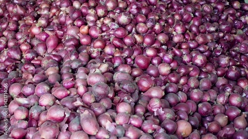 A view of onions piled up for sale. A pile of large red onions in a warehouse.