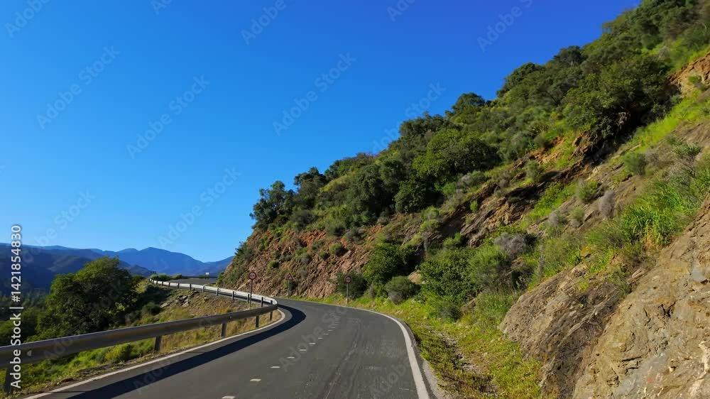 Scenic route winding through a mountainous landscape with vibrant greenery under a clear blue sky in Marbella, Spain Scenic route winding through a mountainous landscape with vibrant greenery under a clear blue sky in Marbella, Spain