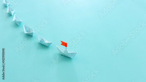 Foto Paper boats following ahead of the leader with red flag