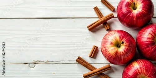 Aromatic Red Apples and Cinnamon Sticks on a Rustic White Wooden Surface