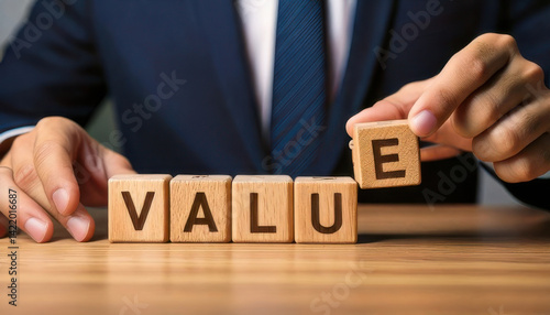 Businessman arranging wooden blocks spelling VALUE on table