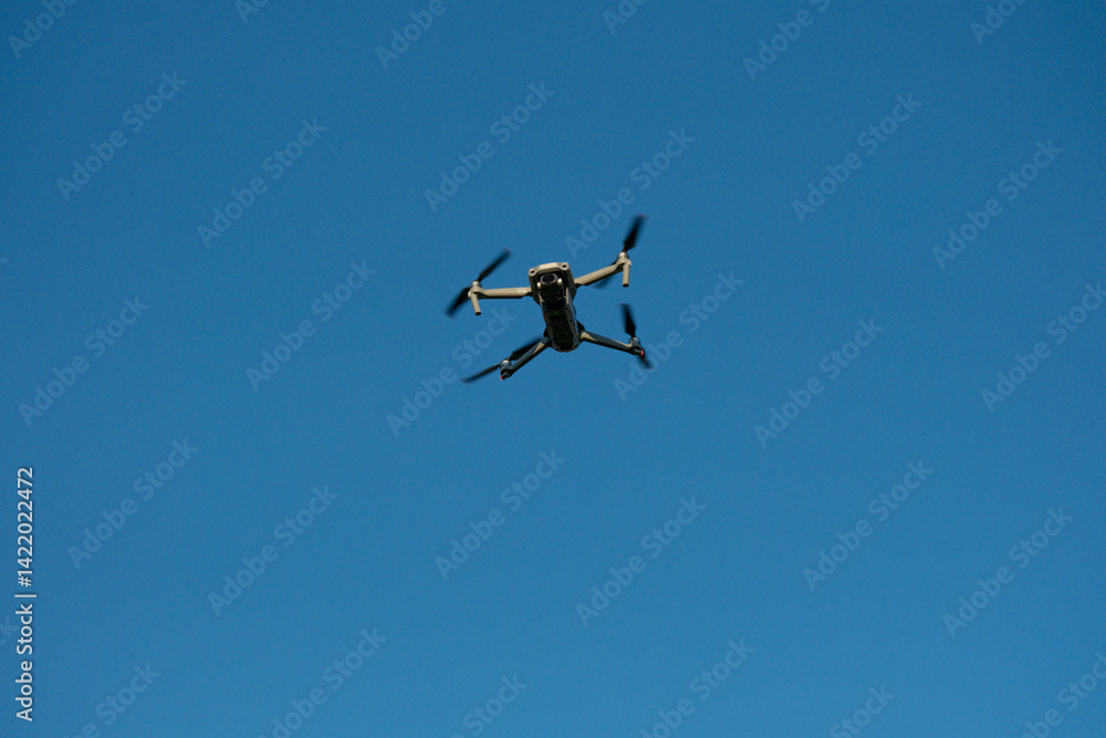 Flying Drone in Clear Blue Sky – Front View of Quadrocopter in Flight Flying Drone in Clear Blue Sky – Front View of Quadrocopter in Flight