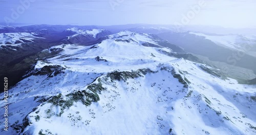 Majestic mountain range covered in snow stretches across the horizon. The bright day reveals the stunning slopes and valleys, reflecting tranquility and natural beauty in winter.