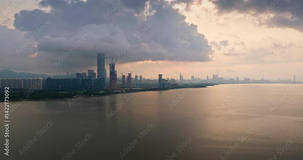 Dramatic aerial view of a modern city skyline bordering a wide bay under a heavy cloudy sky at sunrise in Shenzhen, China. Dramatic aerial view of a modern city skyline bordering a wide bay under a heavy cloudy sky at sunrise in Shenzhen, China.