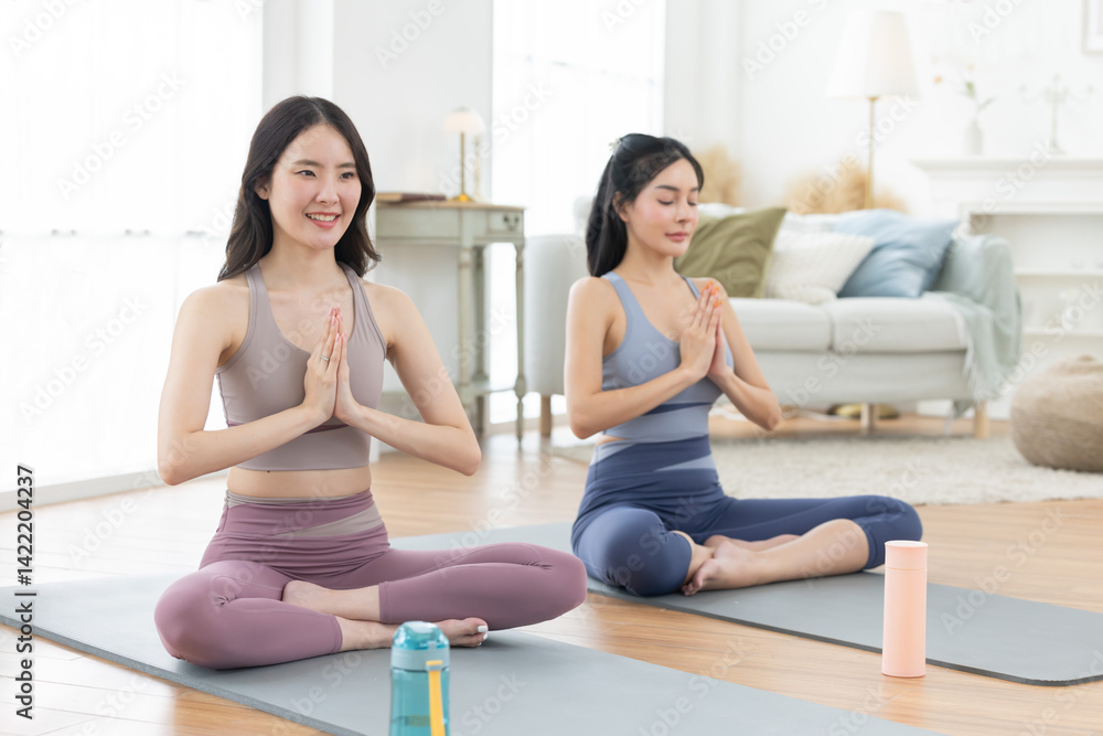 Two asian women are performing yoga pose on yoga mats Two asian women are performing yoga pose on yoga mats