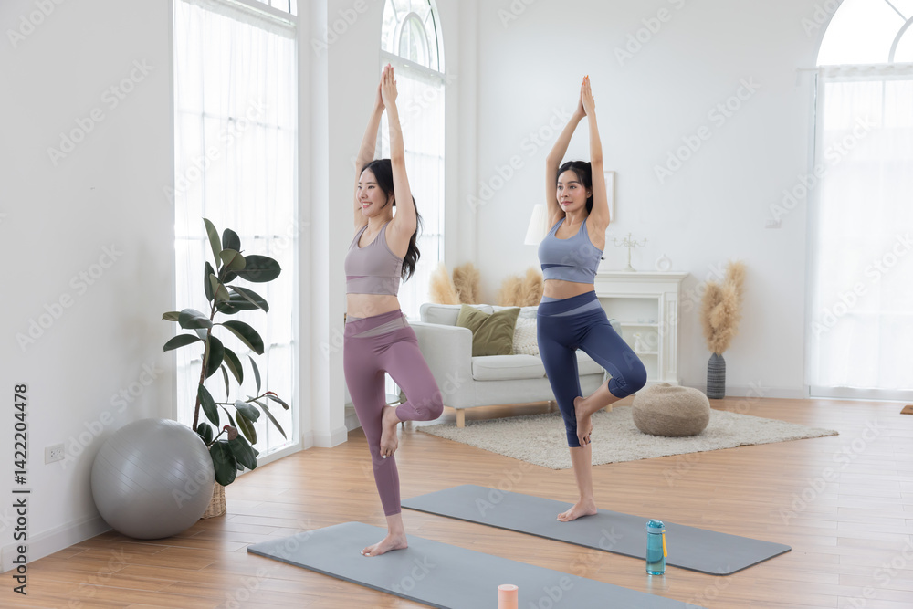 Two asian women are performing yoga pose on yoga mats Two asian women are performing yoga pose on yoga mats