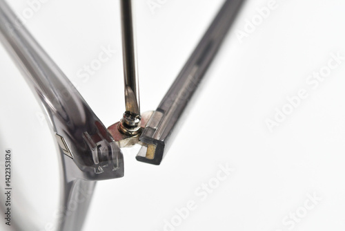 Close up view of a small screwdriver being used to tighten the screw on the arm of a pair of glasses frames