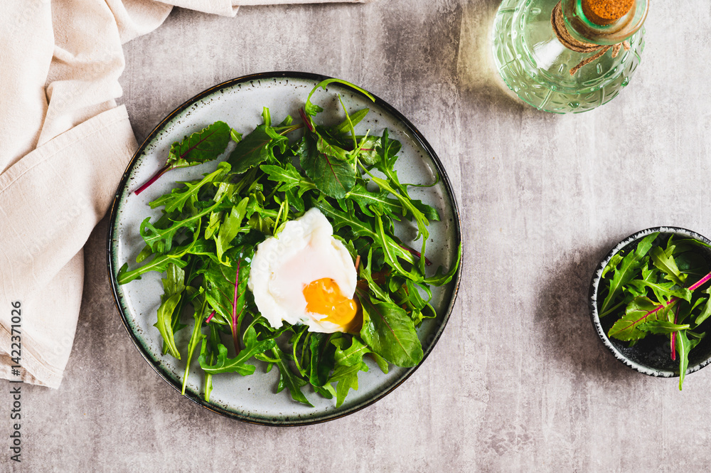 Poached egg in arugula and chard leaves on a plate on a table top view