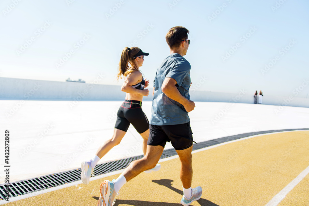 Dynamic Joggers Enjoying a Sunny Day on an Outdoor Track by the Waterfront in a Lively Urban Setting Dynamic Joggers Enjoying a Sunny Day on an Outdoor Track by the Waterfront in a Lively Urban Setting