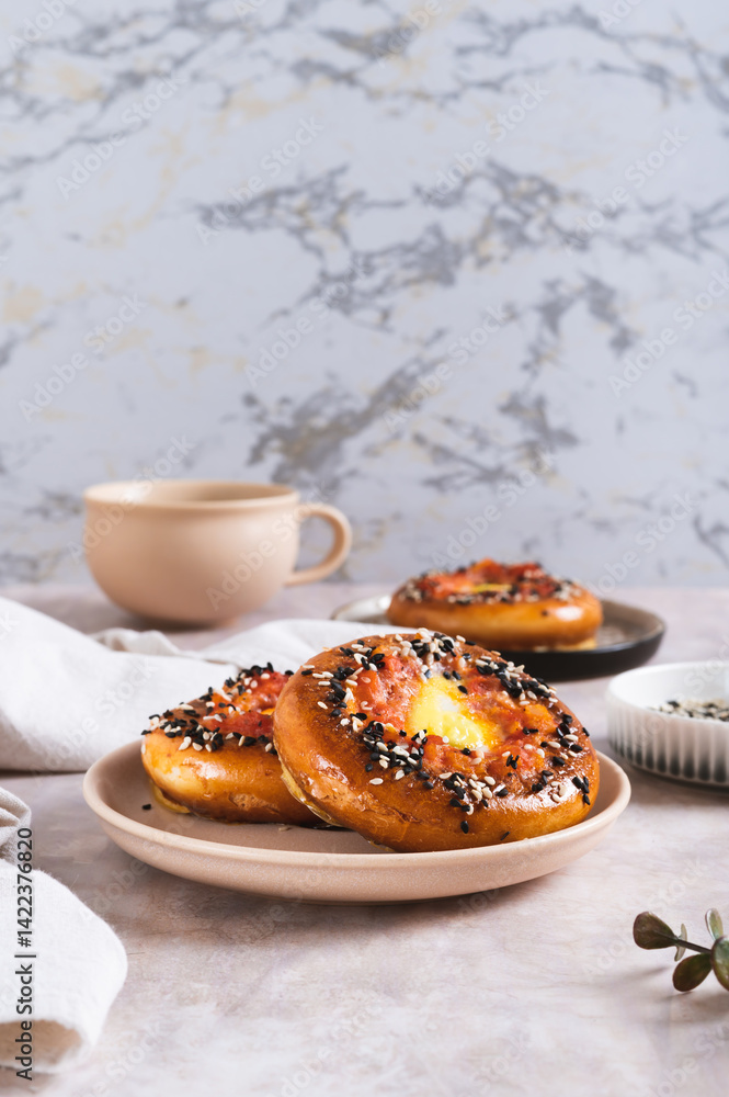 Baked bagels with tomato and quail egg on a plate on the table vertical view
