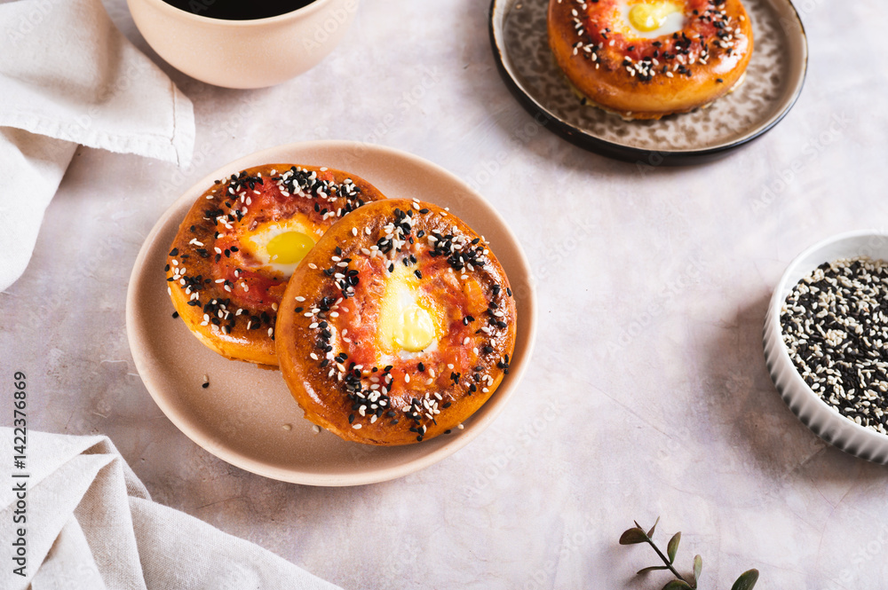 Egg with tomato and sesame seeds baked in bagels on a plate on the table