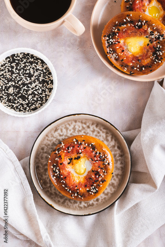 Obraz na płótnie Egg with tomato and sesame seeds baked in bagels on a plate top and vertical view w salonie