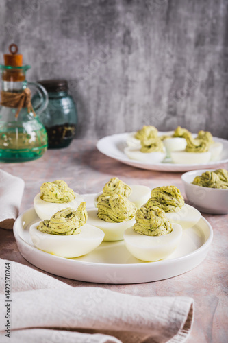 Obraz na płótnie Eggs stuffed with avocado and yolk mixture on a plate on a table vertical view w salonie