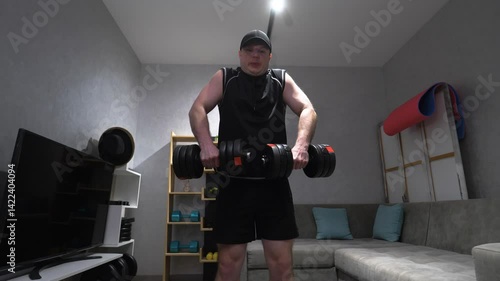 Athlete with dumbbells in his hands, pumping up the trapezius muscle with dumbbells, workout at home with weights. Slow motion.