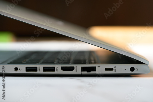 Close up detail of the side panel connectivity on a modern laptop, showing various input and output ports including USB, USB-C, HDMI, and audio jack for peripheral connection on an office desk.